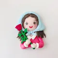 Macro detail of a cute polymer clay girl figurine cake topper holding a red rose for birthday. - Girl with Headscarf
