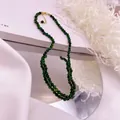 Detail of green tiger eye beaded necklace with gold clasp on mirror reflection - Tiger's Eye / Green