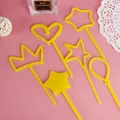 Close-up detail of yellow plastic cake toppers in heart, crown, and star shapes for parties. - Star Crown Balloon Topper - Yellow