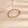 Primo piano di un braccialetto in quarzo rosa fragola con perla centrale intagliata - Stile Coniglio Sdraiato