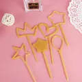 Close-up of gold plastic cake toppers in heart, crown, and star shapes for parties. - Star Crown Balloon Topper - Gold