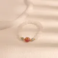Vista macro di bracciale di perle bianche con perla rosa e ciondolo a fiore giallo - nodo di pace