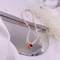 Detailansicht einer Süßwasserperlenkette mit rotem Herz-Zirkonia-Anhänger - Roter Strass-Herz-Stil / Gold