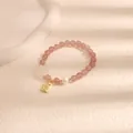Primo piano del bracciale con perline di quarzo fragola, perla e ciondolo dorato - Moneta Portafortuna