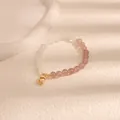 Vista dettagliata di un braccialetto di perline con pietre rosa e ciondolo dorato - Fagiolo d'Oro