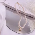 Nahaufnahme einer Reisperlenkette mit einem schimmernden quadratischen Zirkon-Goldanhänger. - Weißer Strass-Quadrat-Stil / Gold