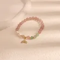 Dettaglio macro di un braccialetto di perle di quarzo rosa con ciondolo a sirena. - Gonna a sirena