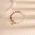 Dettaglio di un braccialetto di perline con pietre rosa e bianche e ciondolo dorato - Acquamarina