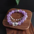 Natural 12mm amethyst bead bracelet with clear quartz accent on a wooden display stand. - 12mm Amethyst Drill Chain Bracelet
