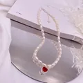 Detailaufnahme einer Reisperlenkette mit einem leuchtend roten Zirkonia-Anhänger in Herzform - Roter Strass-Herz-Stil / Silber