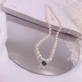 Detaillierte Makroaufnahme einer Süßwasserperlenkette mit einem grünen Herzanhänger - Grüner Strass-Herz-Stil / Silber