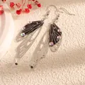 Close-up detail of elegant long butterfly wing earrings with sparkling rhinestones - Silver Frame / Black and White Line