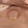 Close-up of strawberry crystal and moonstone bracelet with gold wealth charm - Zhaocai Style