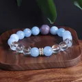 Nahaufnahme von blauem Aquamarin- und Quarz-Perlenarmband auf einem dunklen Holztablett - Aquamarin Armband / Aquamarin Weißer Kristall