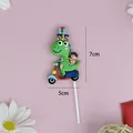 Cartoon green dinosaur cake topper with dimensions shown on pink background - Green Dinosaur Riding Blue Scooter