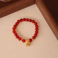 Makroaufnahme eines roten Achat-Armbands mit exquisitem goldenem Lotuskapsel-Anhänger - Naturstein Roter Achat Legierung Lotus Stil