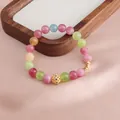 Nahaufnahme eines bunten Turmalin-Kristallarmbands mit einem goldenen Filigran-Anhänger - Transferperlen-Stil / Frucht-Turmalin Transferperle Stil