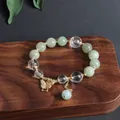 Detailaufnahme eines Jade- und Kristallperlenarmbands mit goldenem Schmetterlingsanhänger. - Schmetterling-Anhänger / Hellgrün (Burma-Jade Schmetterling Quaste)