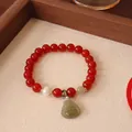 Close-up detail of a red agate bead bracelet featuring a carved green jade Buddha pendant - Natural Red Agate Nephrite Jade Buddha Style