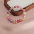 Nahaufnahme eines bunten Kristallarmbands mit einem goldenen Lotusblumen-Anhänger - Multi-Schatz Stil / Frucht-Turmalin Multi-Schatz Stil