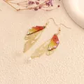 Detail view of elegant gold butterfly wing earrings with gradient resin and rhinestones - Gold Frame / Orange Yellow Rhinestone