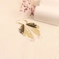 Detailed view of long gold filigree butterfly wing earrings with iridescent rhinestones. - Gold Frame / Green Landscape