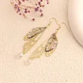 Detailed view of gold butterfly wing earrings with iridescent rhinestones and dried flowers - Gold Frame / Grey Rhinestone