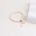 Close-up of freshwater pearl bracelet featuring a gold-framed heart shell pendant. - Heart Tag Style