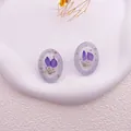 Primer plano de pendientes de resina hechos a mano con flores secas moradas y oro - Violeta Claro