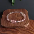 Vue détaillée d'un bracelet Pixiu en quartz fraise sur un support en bois naturel - Style 2