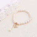 Elegant macro view of the gold bee pendant with zircon crystals on a pearl bracelet - Bee Pendant Style
