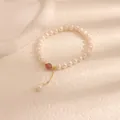 Close-up of freshwater pearl bracelet featuring a strawberry quartz bead and gold dangle - Strawberry Quartz Pearl Style