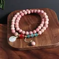 Primer plano de pulsera de cuentas de piedra natural rosa con colgante de jade blanco - Pulsera de Hebilla de Paz de Rodonita