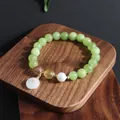 Nahaufnahme eines hellgrünen Edelstein-Armbands mit Jade-Anhänger und einer Perle - Grüne Traube Milchhaube Armband