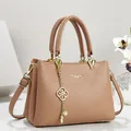 Primo piano di un'elegante borsa rosa con trama in pelle litchi e ciondolo dorato - 26*11*18 / Kaki