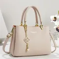 Detailed view of a pinkish-beige leather handbag with an elegant gold floral pearl pendant. - 26*11*18 / Apricot
