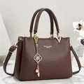 Detail view of brown textured leather handbag with elegant gold flower pendant - 26*11*18 / Coffee