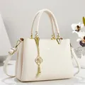Dettaglio di un'elegante borsa a mano in pelle crema con finiture in metallo dorato - 26*11*18 / Bianco avorio