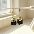 Close-up of gold-plated earrings with natural black tourmaline raw stone pendants. - Drop Earrings / Black Tourmaline