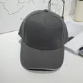 Detail view of a charcoal grey minimalist cotton twill baseball cap on a white desk - 55-60cm / Dark Gray with Contrast Trim