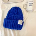 Primo piano di un berretto in maglia a trecce blu con dettaglio etichetta in tessuto - 55-59cm / Blu zaffiro