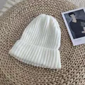Close-up of a white ribbed knit beanie hat presented on a rustic straw background mat. - 54-58cm / White