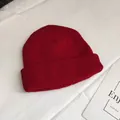 Close-up of a dark red short knitted beanie hat with a classic textured ribbed pattern. - One Size / Burgundy
