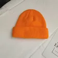 Detailed close-up view of a vibrant orange ribbed knit beanie on a clean white fabric background - One Size / Orange