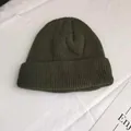 Macro detail of dark green short knitted beanie hat with rib texture on white cloth - One Size / Army Green