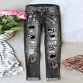 Detailansicht einer zerrissenen Jeans mit Leoparden-Patches und Herzgrafiken. - S / Unterteile / Schwarz mit Leopardenherz-Druck