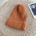Close-up of a ginger orange ribbed knit beanie on a rustic straw mat - 54-58cm / Orange