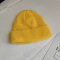 Detailed view of a bright yellow ribbed knit beanie placed on white fabric - One Size / Bright yellow