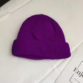 Detail view of a vibrant purple ribbed knit beanie hat on a white surface - One Size / Bright Purple