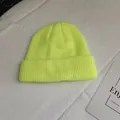 Detail view of a vibrant neon yellow rib-knit beanie hat on white fabric surface - One Size / Neon Yellow